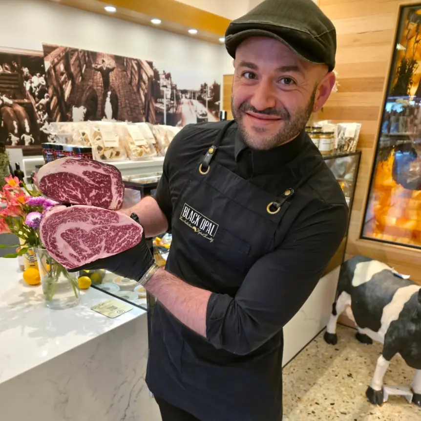 Mathew Bonnici behind the counter at 308 Racecourse Road, in apron and flat cap